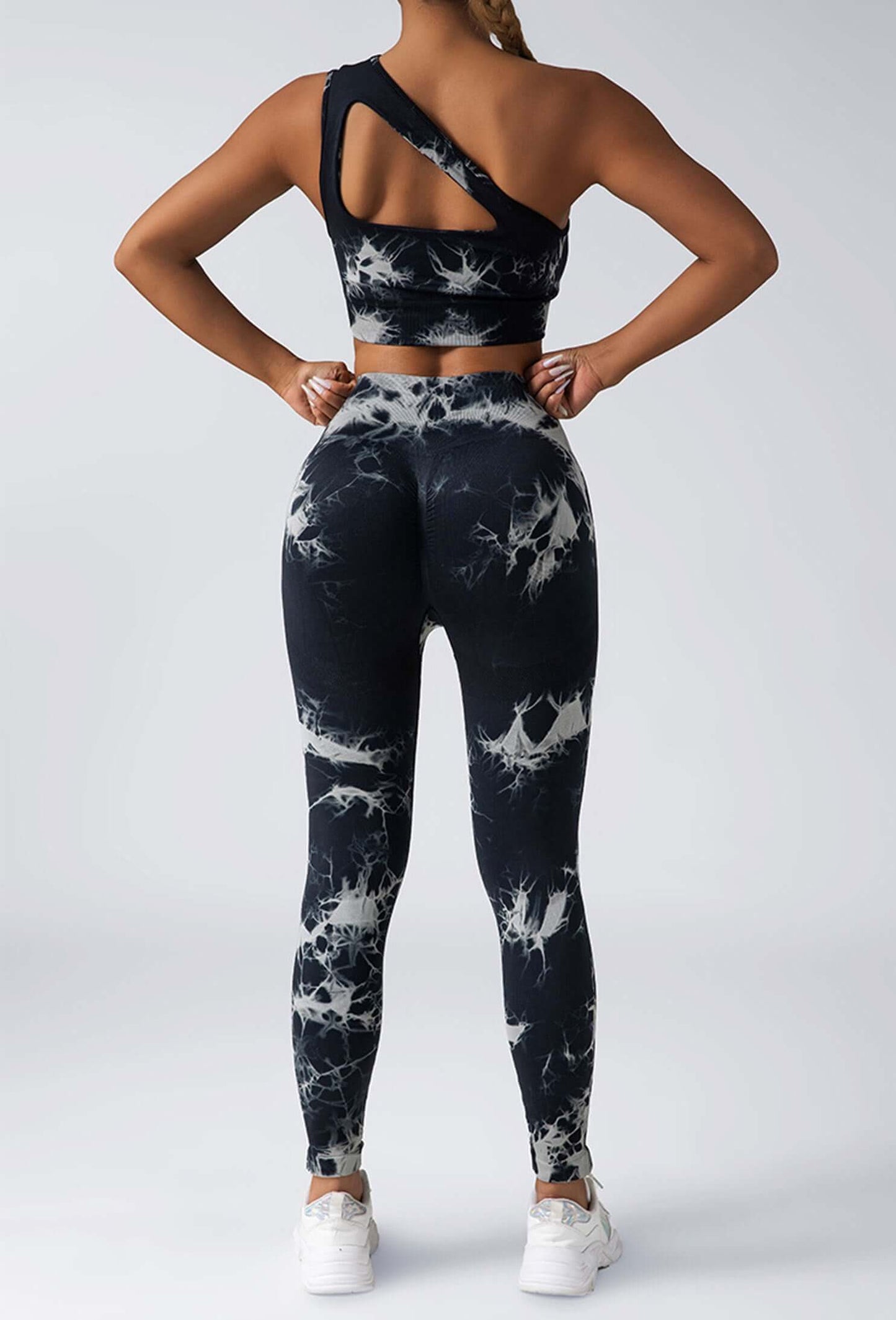 Person wearing black and white tie-dye athletic leggings and sports bra on a light gray background