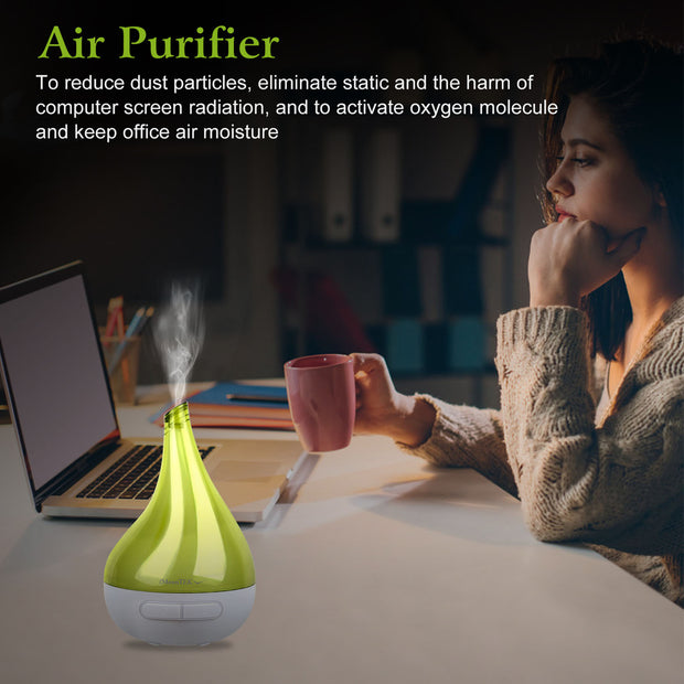 Woman sitting at a desk with an air purifier, laptop, and pink mug.