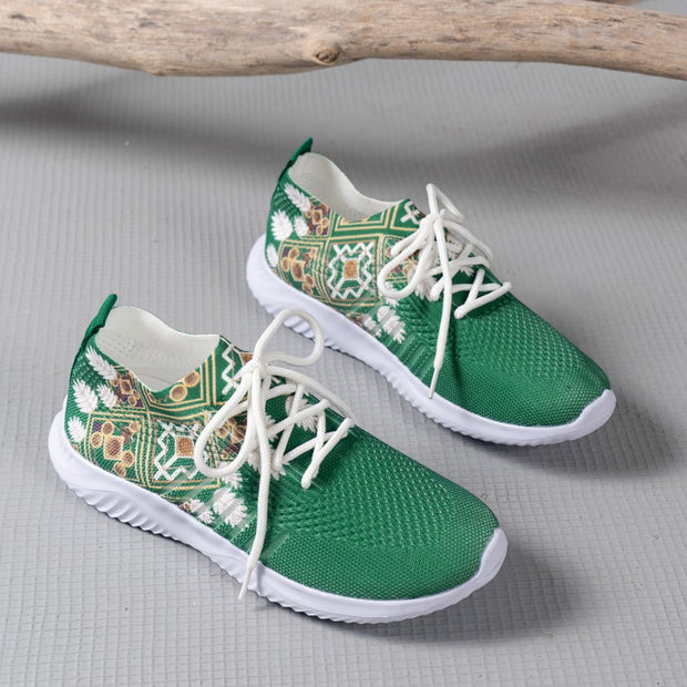 Gree sneakers with white soles and patterned design on a gray surface