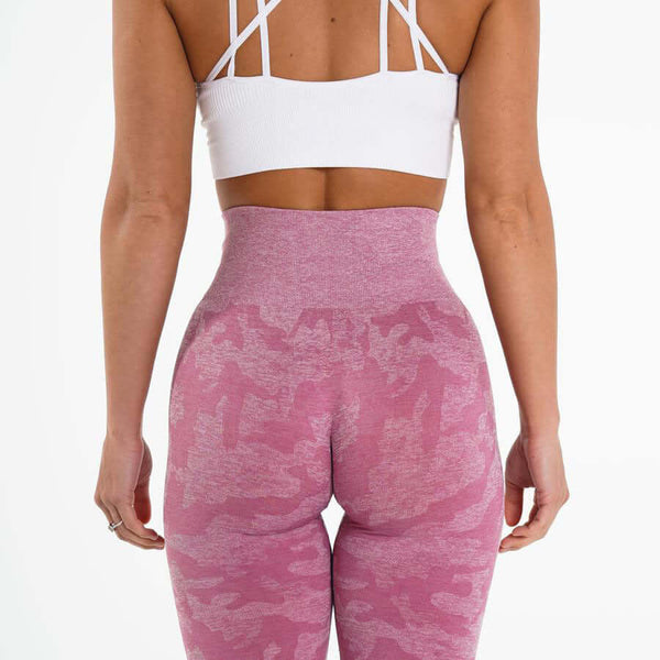 Back view of woman in pink yoga leggings and white sports bra, showcasing style and fit for comfort and flexibility.