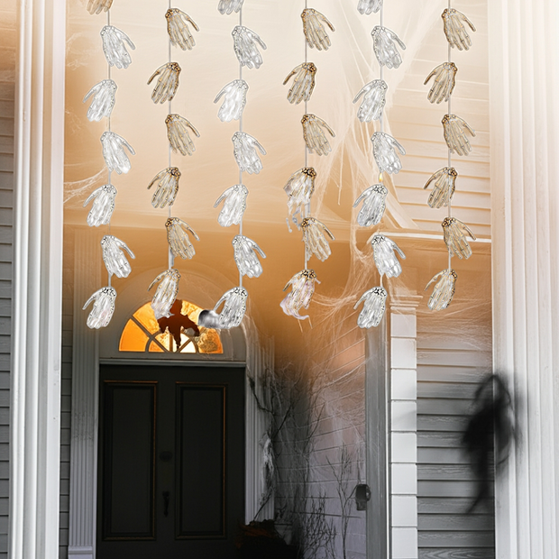 Decorative hanging skeleton hands with a warm glow in front of a door.