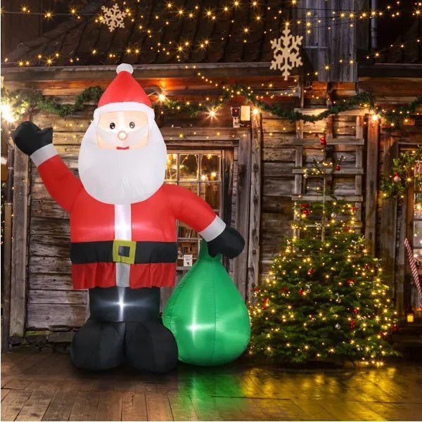 Inflatable Santa Claus decoration with a green sack in front of a Christmas tree and wooden wall.