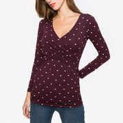 Woman wearing a burgundy long-sleeve top with white polka dots on a white background