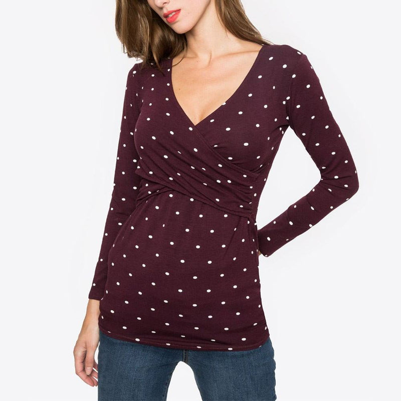 Woman wearing a burgundy long-sleeve top with white polka dots on a white background