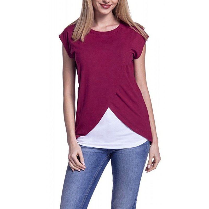 Woman wearing a maroon top with a white layer and blue jeans on a white background