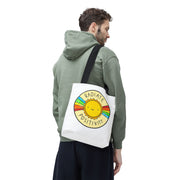 Person wearing a green hoodie with a tote bag featuring a sun design and text.