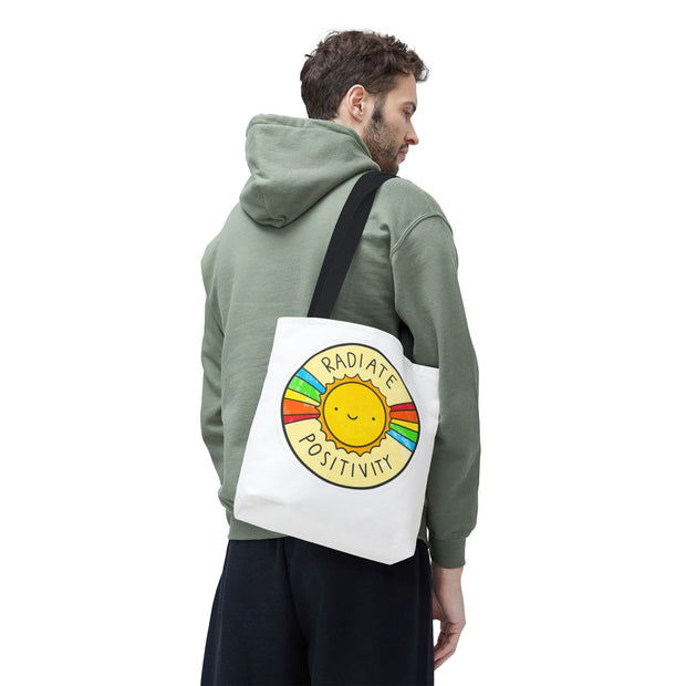 Person wearing a green hoodie with a tote bag featuring a sun design and text.