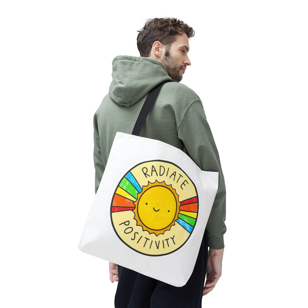 Man carrying a tote bag with a sun design and 'Radiate Positivity' text on a white background
