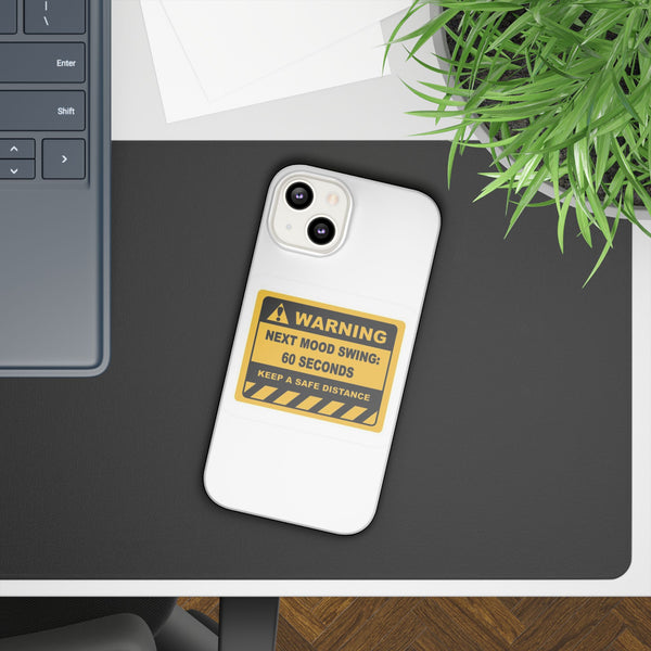 Phone case with a warning design on a desk next to a laptop and plant