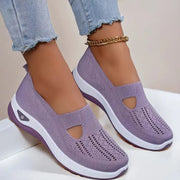 Purple slip-on shoes with white soles worn by a person on a light background