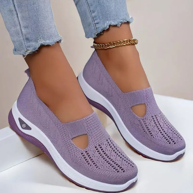 Purple slip-on shoes with white soles worn by a person on a light background