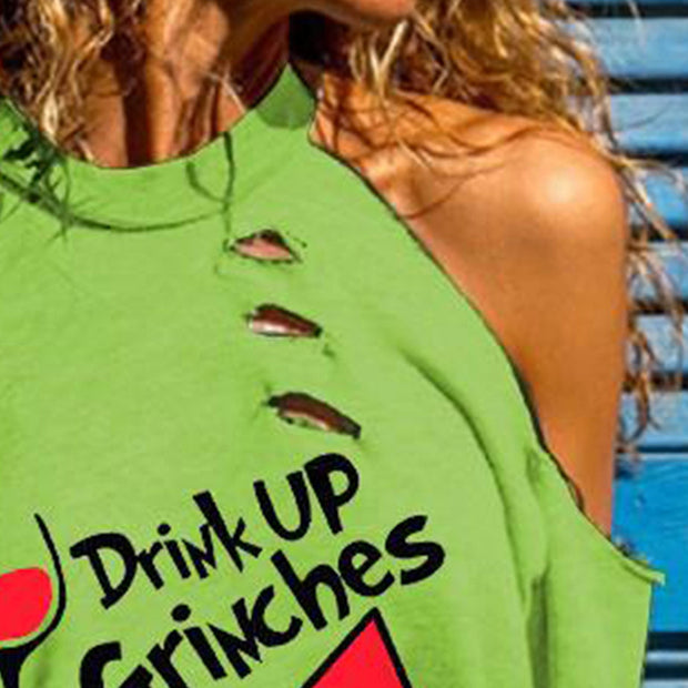 Person wearing a green distressed t-shirt with 'Drink Up Grinches' text and heart design.