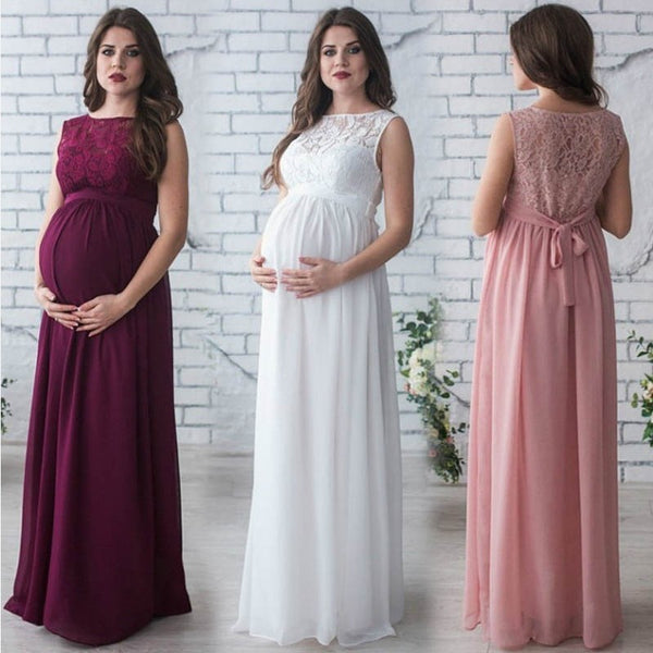 Three women wearing long, elegant dresses in front of a white brick wall.