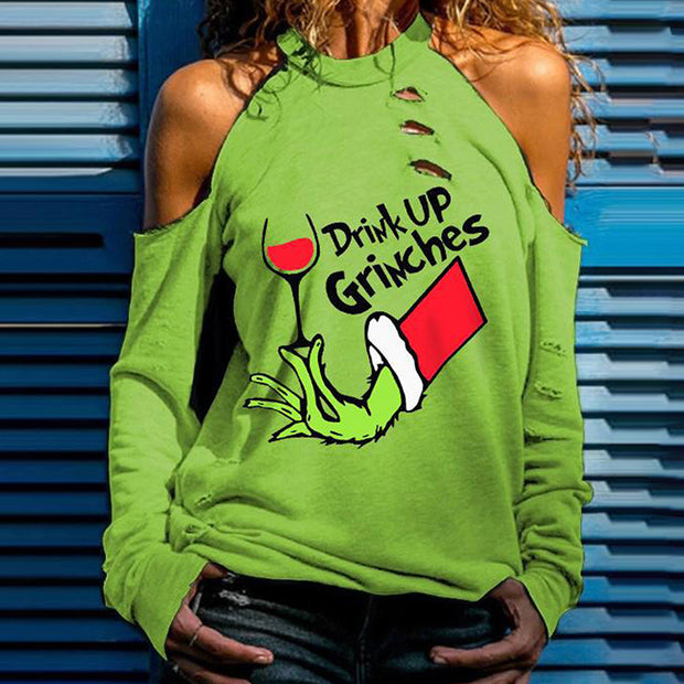 Person wearing a green sweatshirt with 'Drink Up Grinches' text and graphic design.