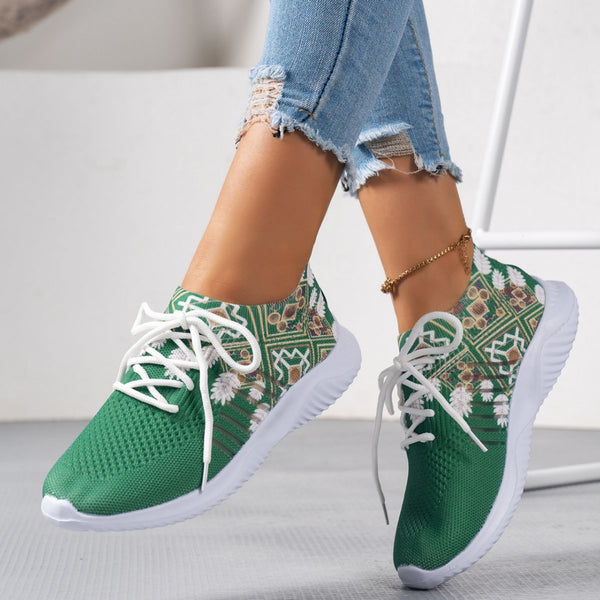 Green patterned sneakers with white laces worn by a person on a light background