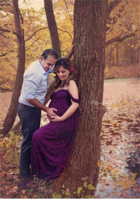 Man and woman in a purple dress standing next to a tree in an autumn setting