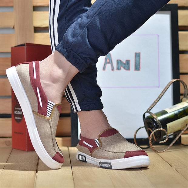 Person wearing beige and red slip-on shoes on a wooden floor.