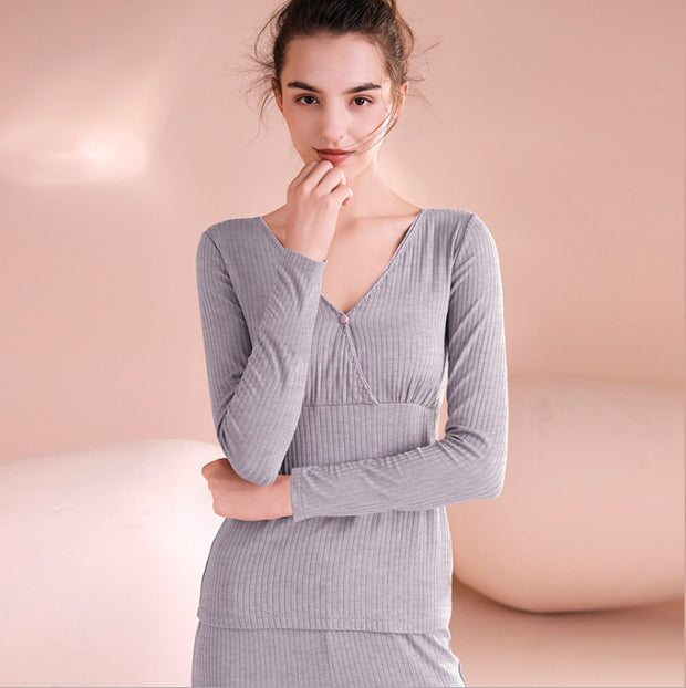Woman wearing a gray ribbed long-sleeve top against a pink background