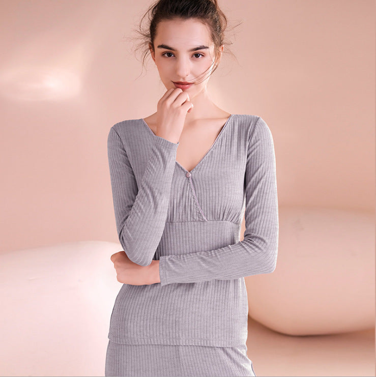 Woman wearing a gray ribbed long-sleeve top against a pink background