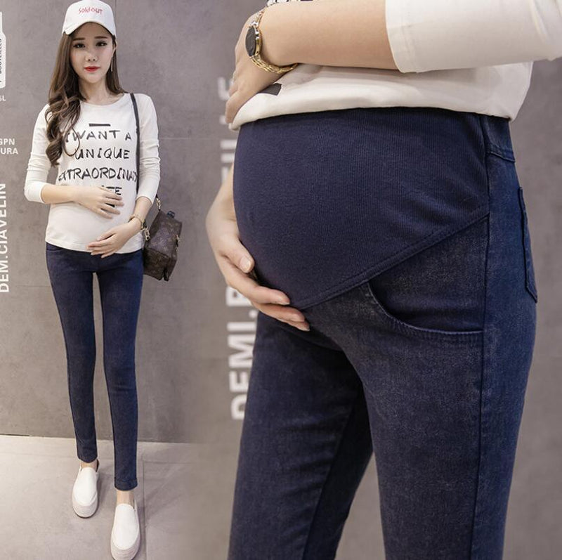 Woman wearing dark blue jeans with a gray background