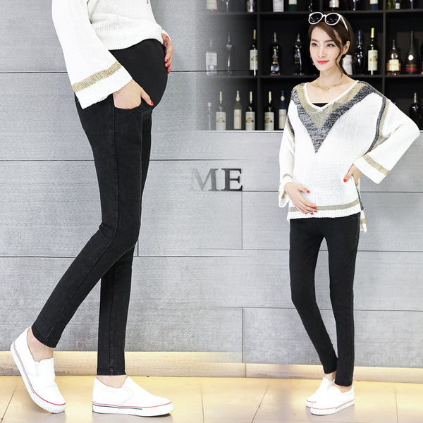 Two women wearing black pants and white tops in a store setting.