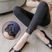 Person wearing black jeans with lace cuffs sitting on a wooden floor.
