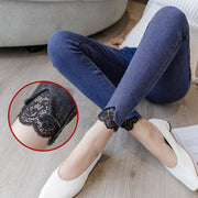 Person wearing blue jeans with lace details sitting on a floor.