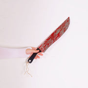 Hand holding a large knife with a bloody blade on a white background