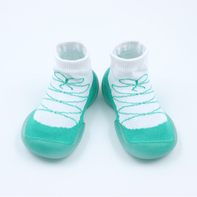 Pair of baby socks with green sole and white top on a light gray background