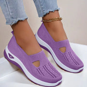 Purple slip-on shoes with white soles worn by a person on a light background