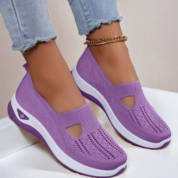 Purple slip-on shoes with white soles worn by a person on a light background