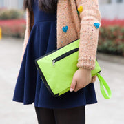 Person holding a bright green clutch bag outdoors