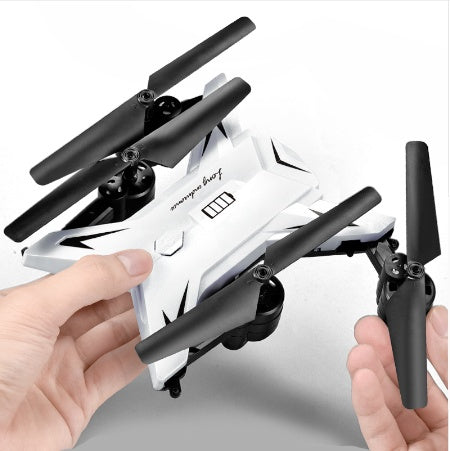 Small white drone with black propellers held by a person's hands on a light gray background