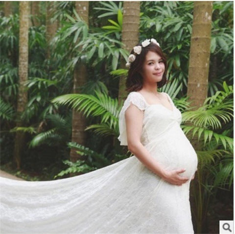 Pregnant woman in a white dress standing in a lush green forest