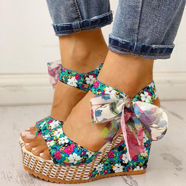Colorful floral wedge sandals with a bow on a light background