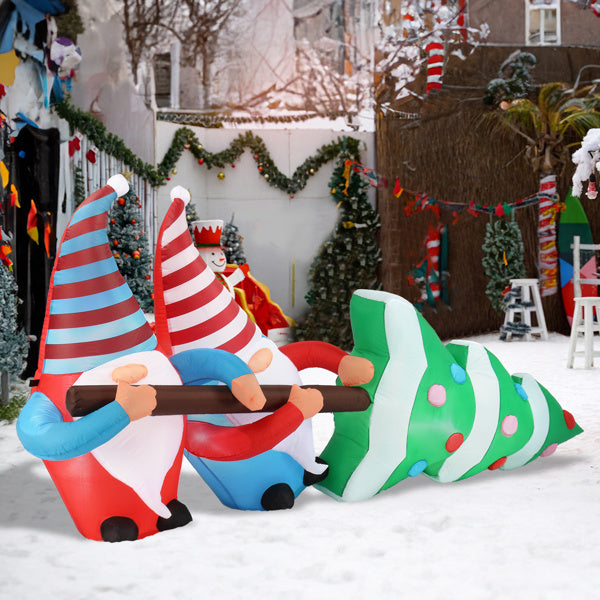 Inflatable Christmas gnomes and tree in a snowy outdoor setting with holiday decorations.