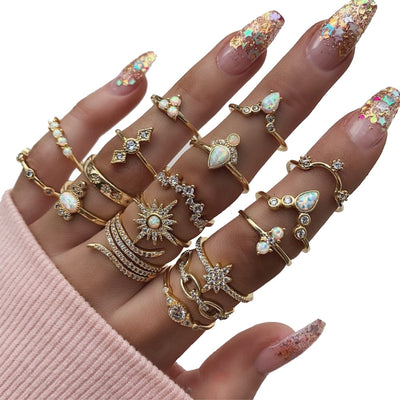 Hand wearing multiple gold rings with gemstones on a white background