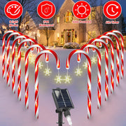 Candy cane-shaped outdoor lights with solar panel in front of a house during Christmas.