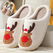 Pair of white slippers with reindeer face design on a soft surface.
