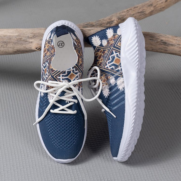 Blue sneakers with white soles and patterned design on a gray surface