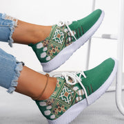 Green patterned sneakers with white laces worn by a person on a light background