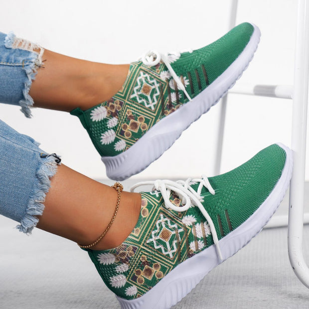 Green patterned sneakers with white laces worn by a person on a light background