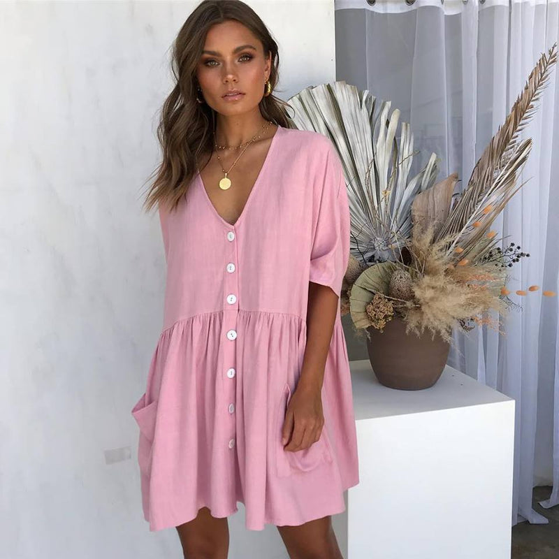 Woman wearing a pink dress standing in a room with decorative plants.