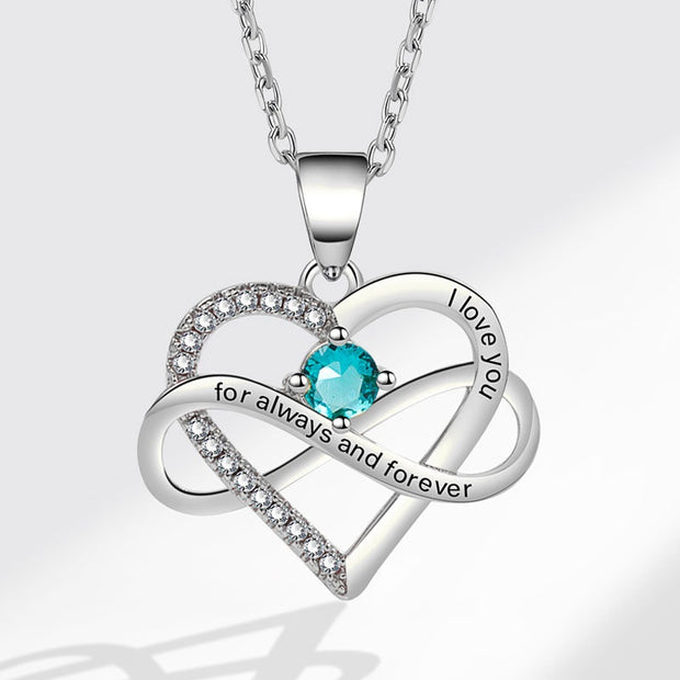 Heart-shaped pendant necklace with blue gemstone and 'I love you' engraving on a light gray background