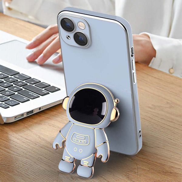 Phone case with an astronaut design on a desk next to a laptop