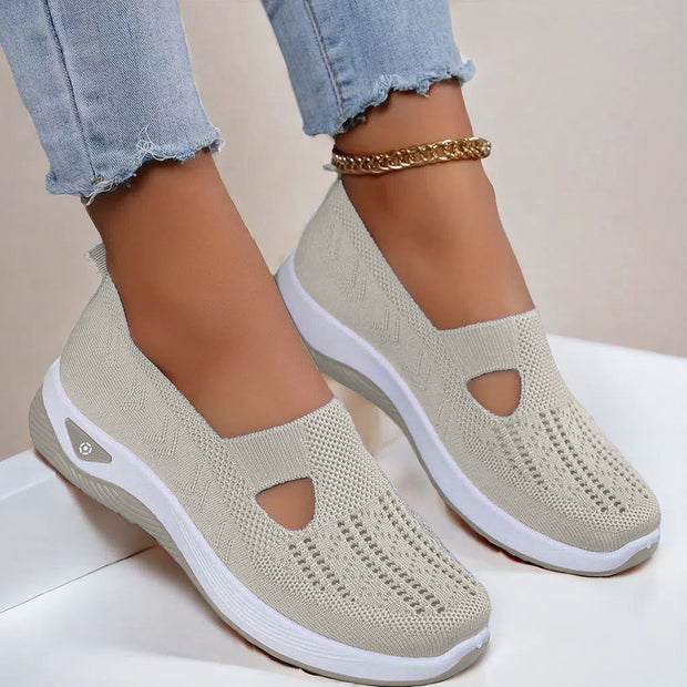 Beige slip-on shoes with white soles worn by a person on a light background