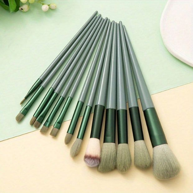 Set of makeup brushes with green and gray handles on a light green and beige background