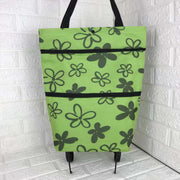 Green tote bag with black floral pattern on a white tiled floor.