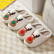 Pair of white slippers with reindeer design on a checkered floor.