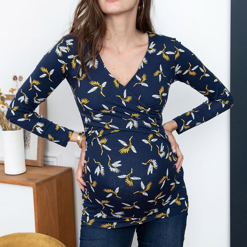 Woman wearing a navy blue dress with yellow and white floral pattern indoors.